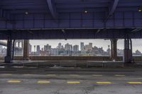 an empty parking lot is surrounded by two fenced off areas and a view of the city