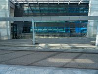 an empty parking lot with a glass building in the background and stairs on either side