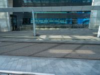 an empty parking lot with a glass building in the background and stairs on either side