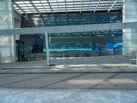 an empty parking lot with a glass building in the background and stairs on either side