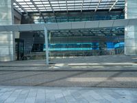 an empty parking lot with a glass building in the background and stairs on either side