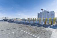 parking lot filled with lots of parking poles near tall buildings near a parking area and airport