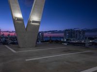 the large sculpture is in front of a city view at night, with two buildings to the left of it