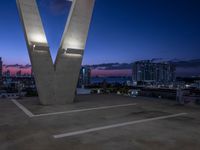 the large sculpture is in front of a city view at night, with two buildings to the left of it