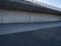 a skateboard sits outside a concrete structure that is next to a street area with a bench