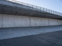 a skateboard sits outside a concrete structure that is next to a street area with a bench