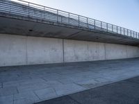 a skateboard sits outside a concrete structure that is next to a street area with a bench