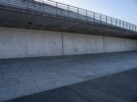 a skateboard sits outside a concrete structure that is next to a street area with a bench