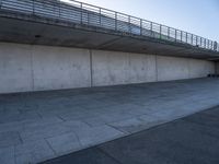 a skateboard sits outside a concrete structure that is next to a street area with a bench