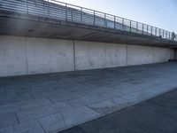 a skateboard sits outside a concrete structure that is next to a street area with a bench