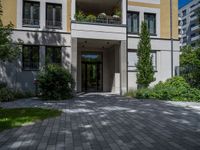 a residential driveway with a bench and bushes in between buildings and green grass on either side