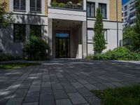 a residential driveway with a bench and bushes in between buildings and green grass on either side