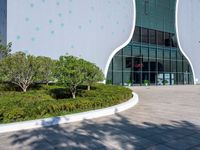 a building with a lot of windows next to bushes and trees with polka dots on it