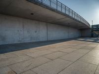 a skateboarder riding on a cement ramp next to a city street under a bridge