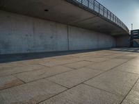 a skateboarder riding on a cement ramp next to a city street under a bridge