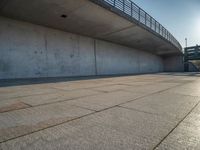 a skateboarder riding on a cement ramp next to a city street under a bridge