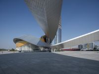 an empty concrete plaza with a futuristic building in the background and a blue sky overhead