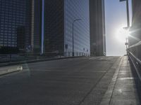 the sun is setting on a very big city skyline in the afternoon sun reflects off the glass windows and sidewalk