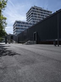 the street is empty in front of a high - rise building with a ramp leading up to the sidewalk