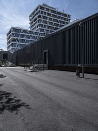 the street is empty in front of a high - rise building with a ramp leading up to the sidewalk