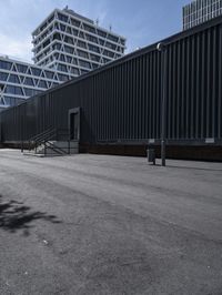 the street is empty in front of a high - rise building with a ramp leading up to the sidewalk