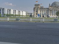 a person riding a skate board on the road by the german flag flying in the air