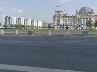 a person riding a skate board on the road by the german flag flying in the air