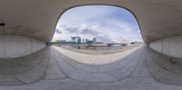 a view through the center of a concrete bridge on an overcast day with people and buildings in the background