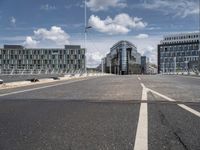 the asphalt roadway is almost empty in the daytime time and cloudy sky above the buildings