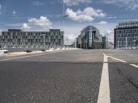 the asphalt roadway is almost empty in the daytime time and cloudy sky above the buildings