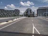 the asphalt roadway is almost empty in the daytime time and cloudy sky above the buildings