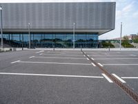 a parking lot with a light post on the corner and an outside building with a glass - walled facade