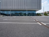 a parking lot with a light post on the corner and an outside building with a glass - walled facade