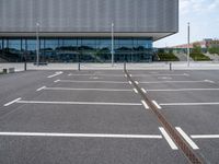 a parking lot with a light post on the corner and an outside building with a glass - walled facade