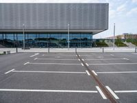 a parking lot with a light post on the corner and an outside building with a glass - walled facade