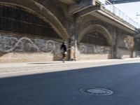 graffiti covered brick wall and gate under an overpass in an urban area with sun light