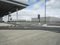 a view of a parking lot, including two buildings and a highway with traffic going down it
