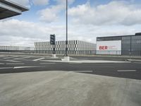 a view of a parking lot, including two buildings and a highway with traffic going down it