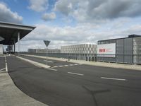 a view of a parking lot, including two buildings and a highway with traffic going down it