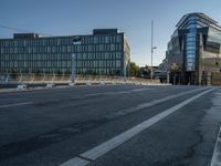 several large glass buildings stand around on a deserted street in a city with a concrete sidewalk that goes over