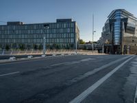 several large glass buildings stand around on a deserted street in a city with a concrete sidewalk that goes over