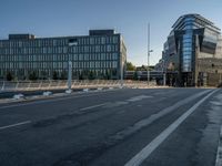 several large glass buildings stand around on a deserted street in a city with a concrete sidewalk that goes over