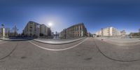 a fisheye lens photo of some buildings and a blue sky in an intersection with cars