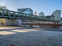 a skateboarder riding on a cement ramp next to a city street under a bridge