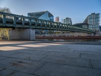 a skateboarder riding on a cement ramp next to a city street under a bridge