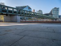 a skateboarder riding on a cement ramp next to a city street under a bridge