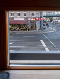 a view out the window of a street scene with traffic and pedestrians on it and a bridge