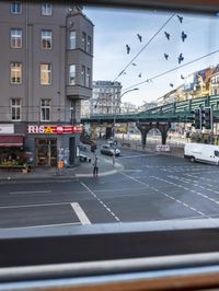 a view out the window of a street scene with traffic and pedestrians on it and a bridge