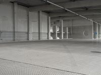 a parking garage with a metal floor and fire hydrant in it that is empty