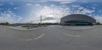 a circular lens shot of a building and street area in a city square with lots of vehicles in the parking lot